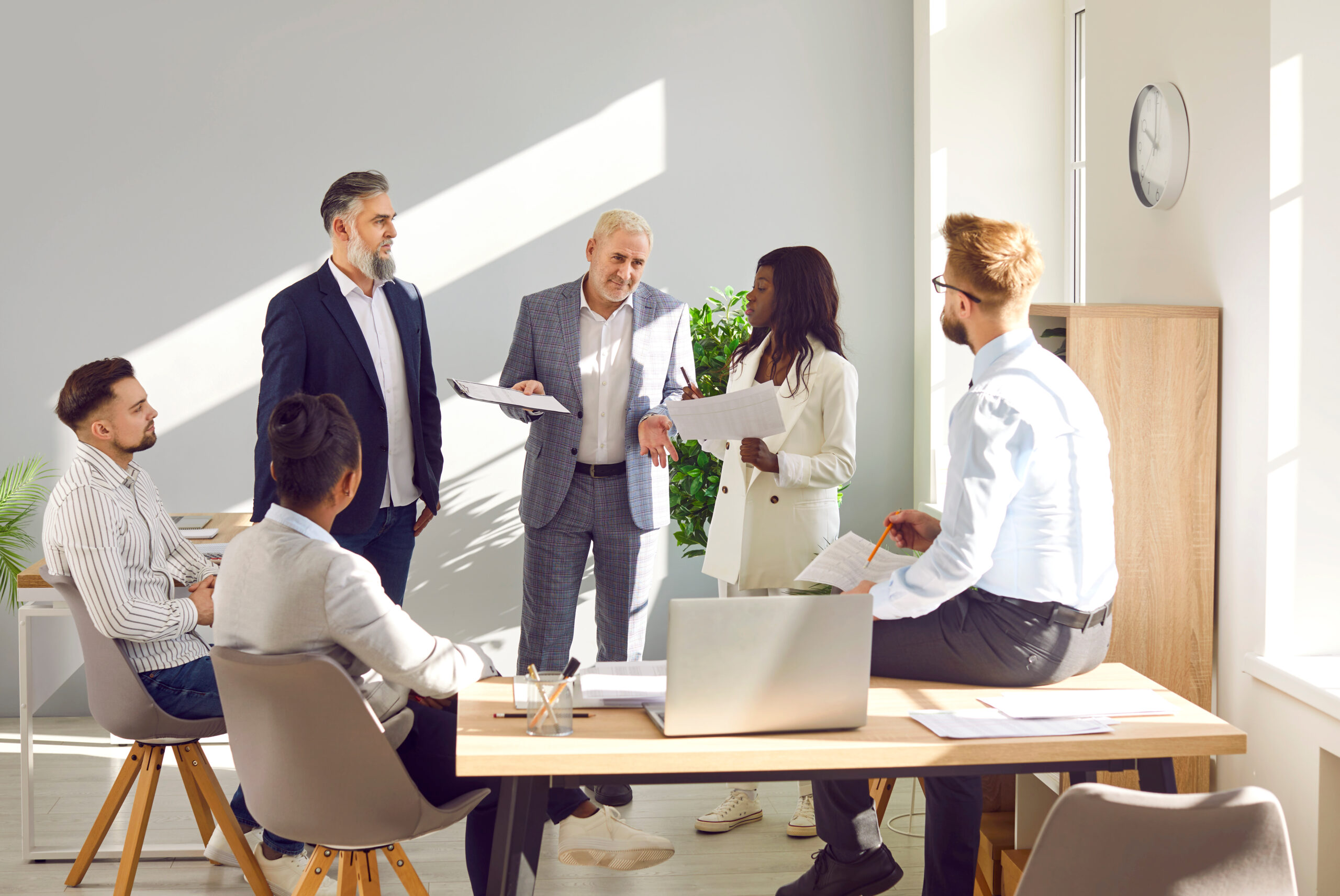 Diverse multiracial corporate business team having work meeting together. Group of six young and senior mixed race multiethnic people discussing their strategy in company office with laptop